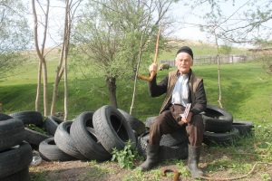 Ciobanul de 100 de ani explicând „sistemul de semnalizare vizuală” pe care-l aplică pentru a le spune „subordonaţilor” de la stână unde să ducă turmele pe munte la păscut